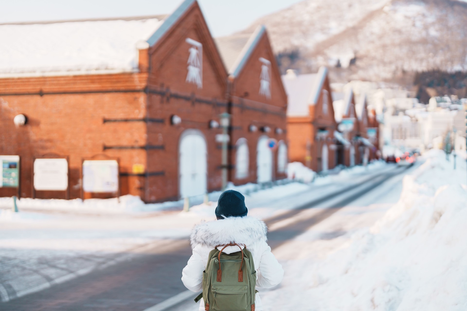 Woman tourist Visiting in Hakodate, Traveler in Sweater sightseeing Kanemori Red Brick Warehouse with Snow in winter. landmark and popular for attractions in Hokkaido,Japan.Travel and Vacation concept